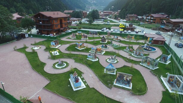 A large, open plaza with a central fountain, surrounded by green lawns and pathways.
