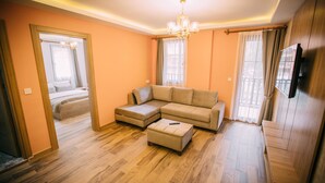 A modern living room with a sectional sofa, ottoman, wooden flooring, and a television.