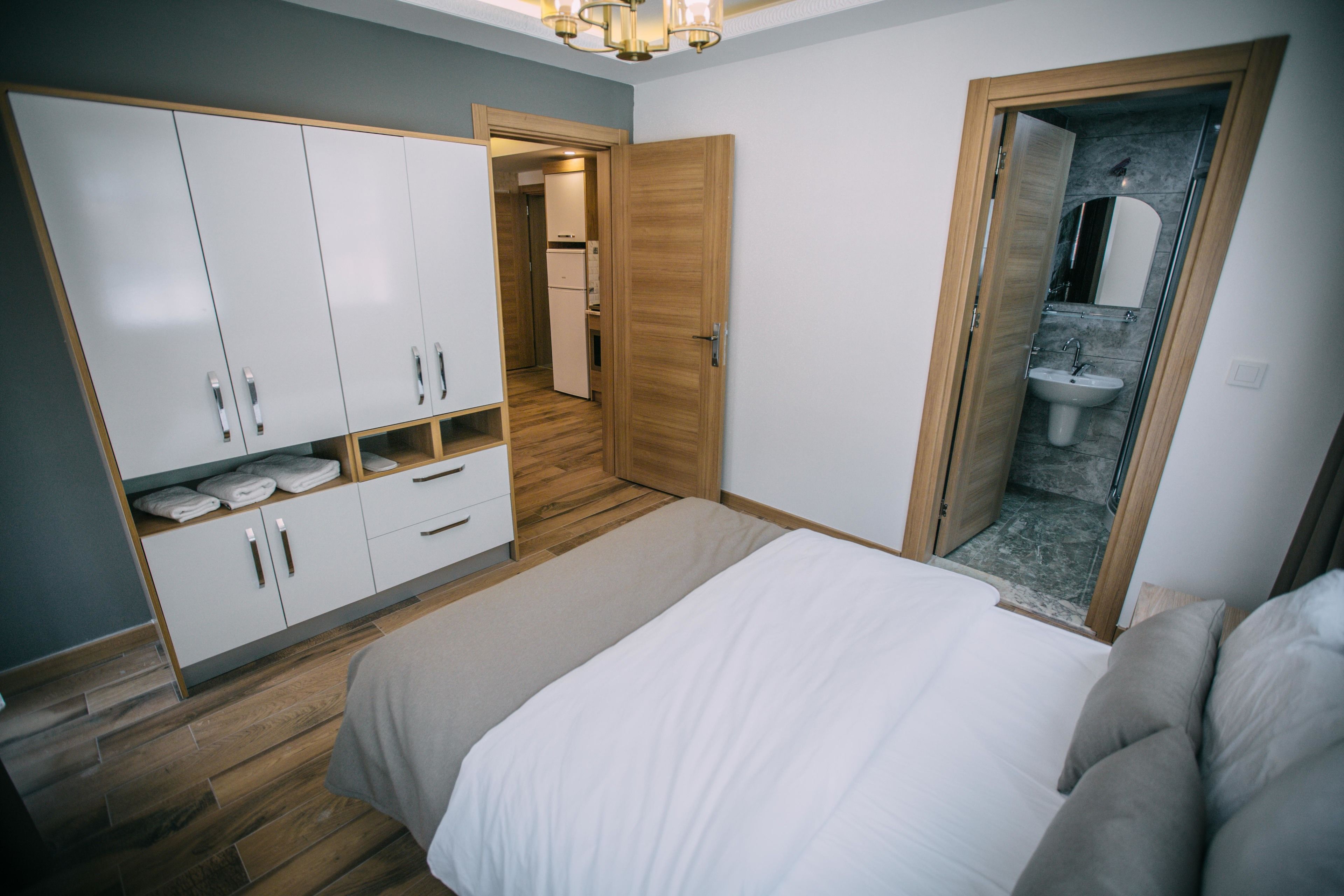 Un dormitorio con cama, armario y baño visible a través de una puerta abierta.
