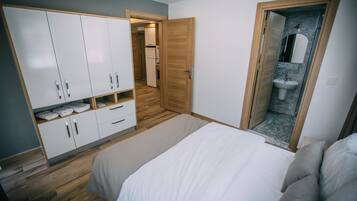 Un dormitorio con cama, armario y baño visible a través de una puerta abierta.