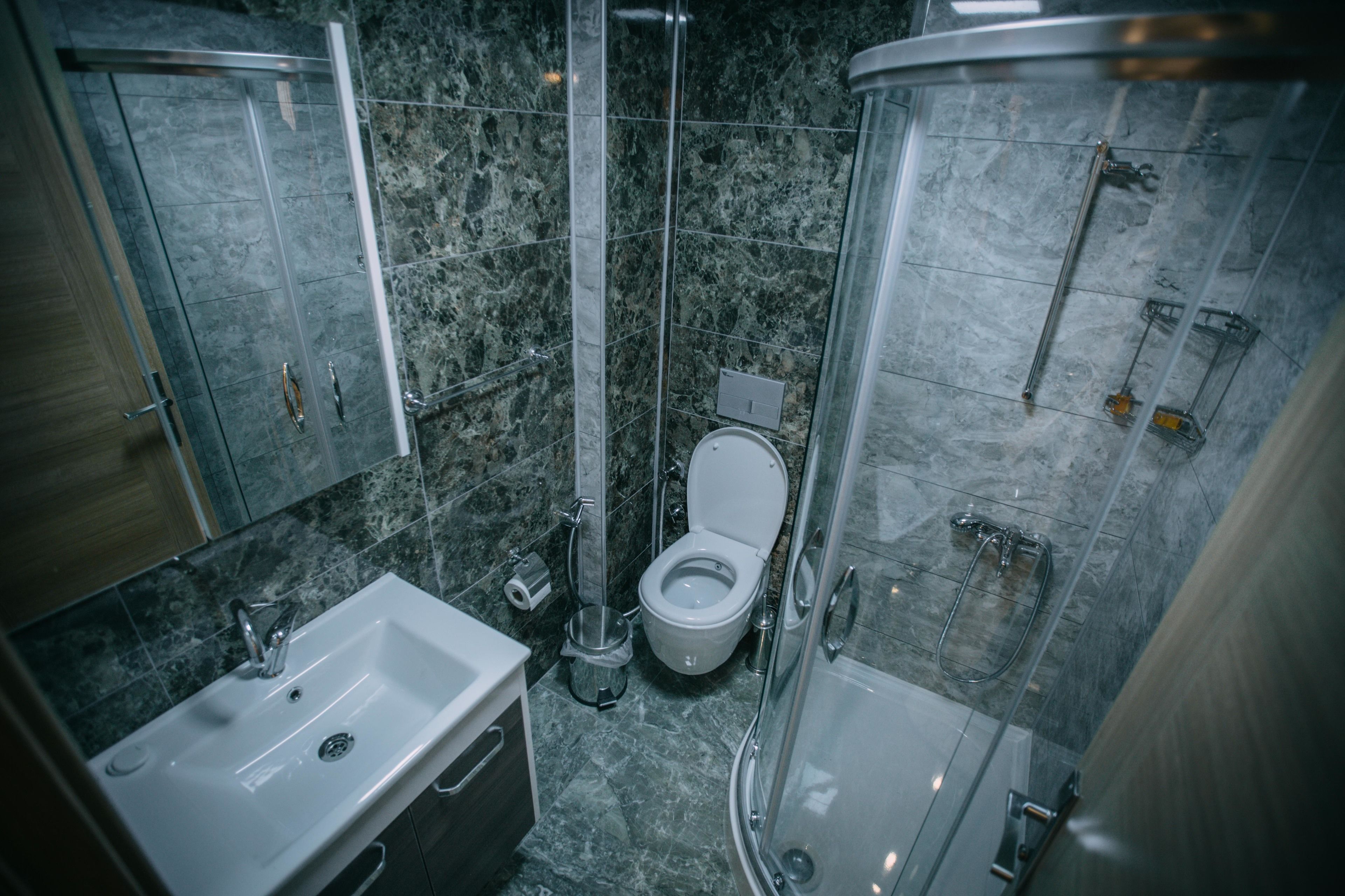 Un baño moderno con lavamanos, inodoro y ducha con mampara de vidrio.