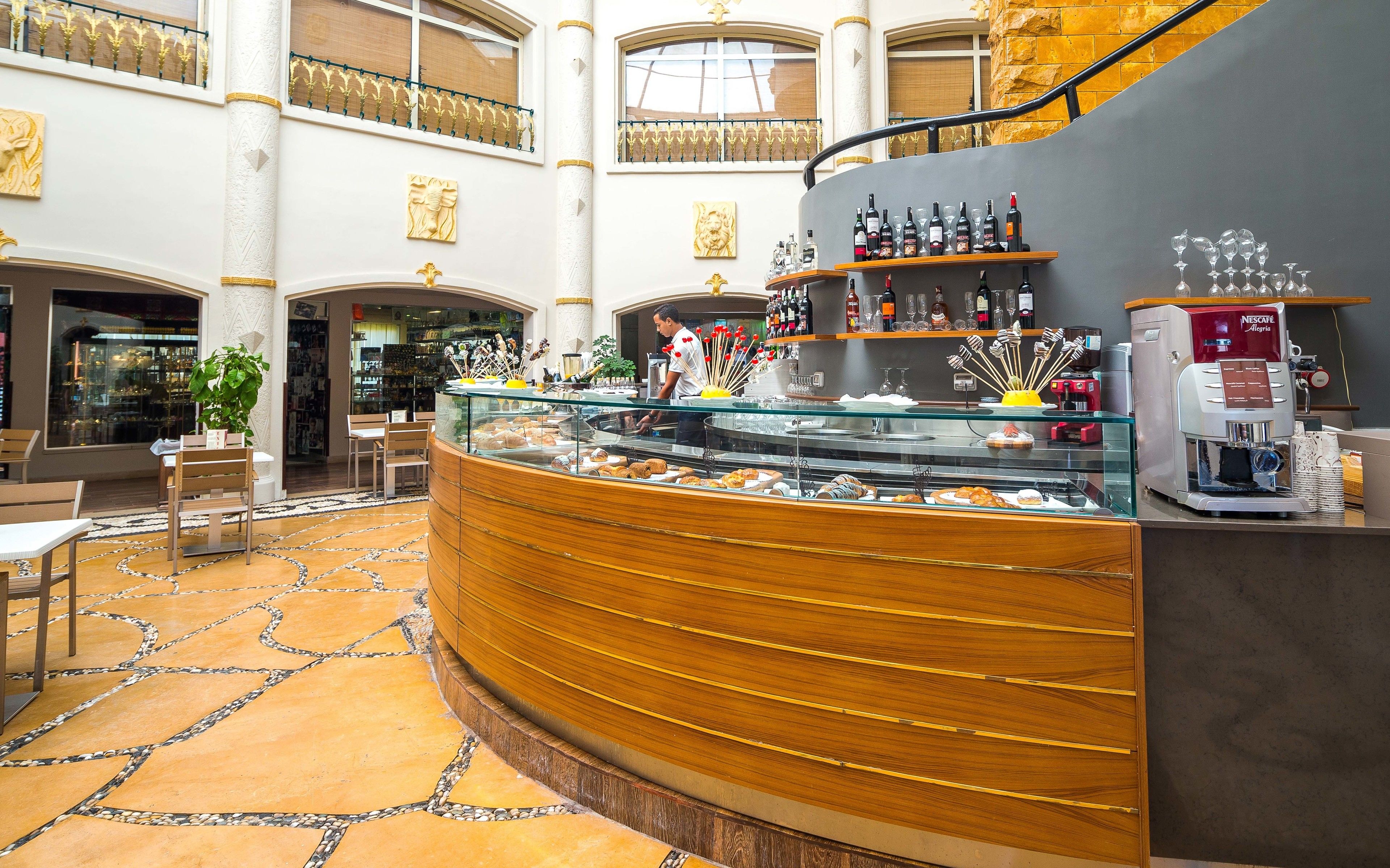 Een hotellobby met een gebogen balie waar gebak en een koffieapparaat staan.