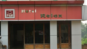 Um hotel chamado "Relax", com fachada vermelha e grandes janelas.