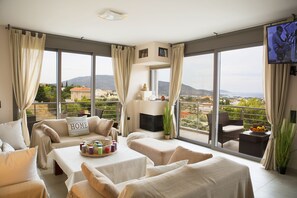 A spacious balcony with a sofa, a table with a fruit bowl, and a TV. - Villa Sunset Lagonisi (Saronikos)