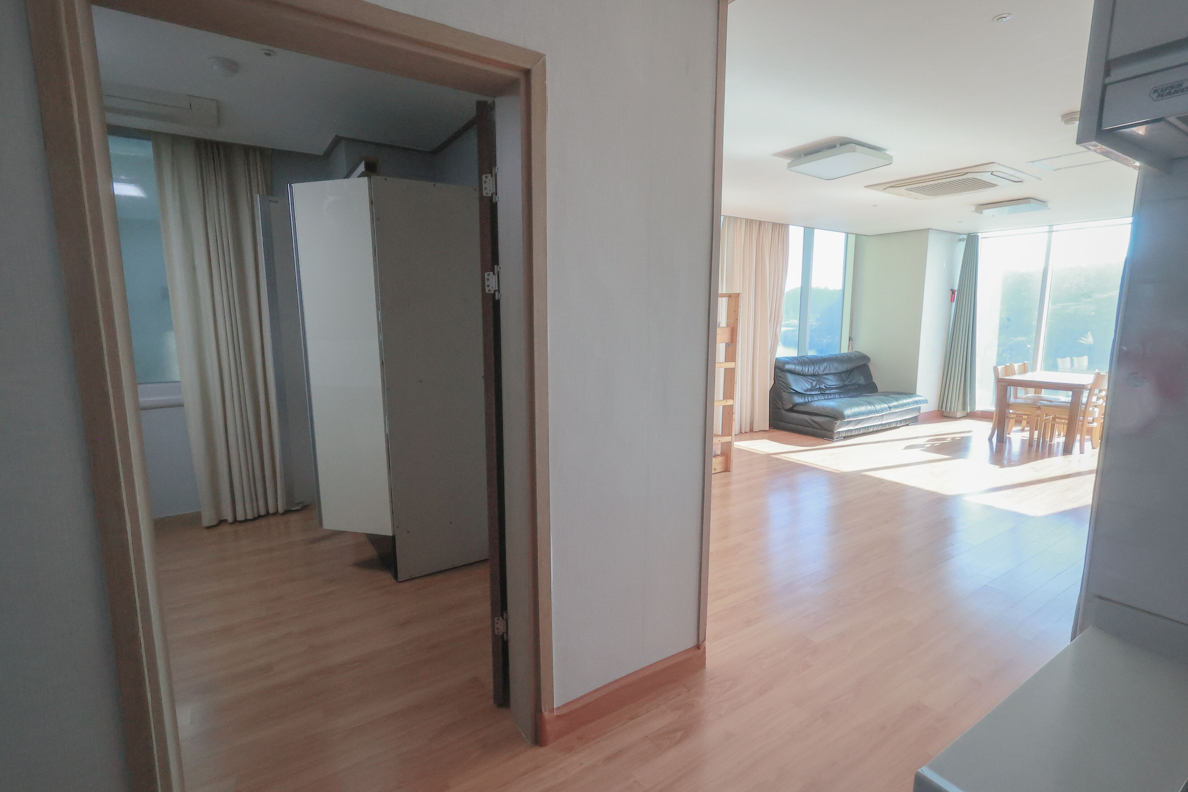 A spacious living area with a wooden floor, a sofa, and a dining table.