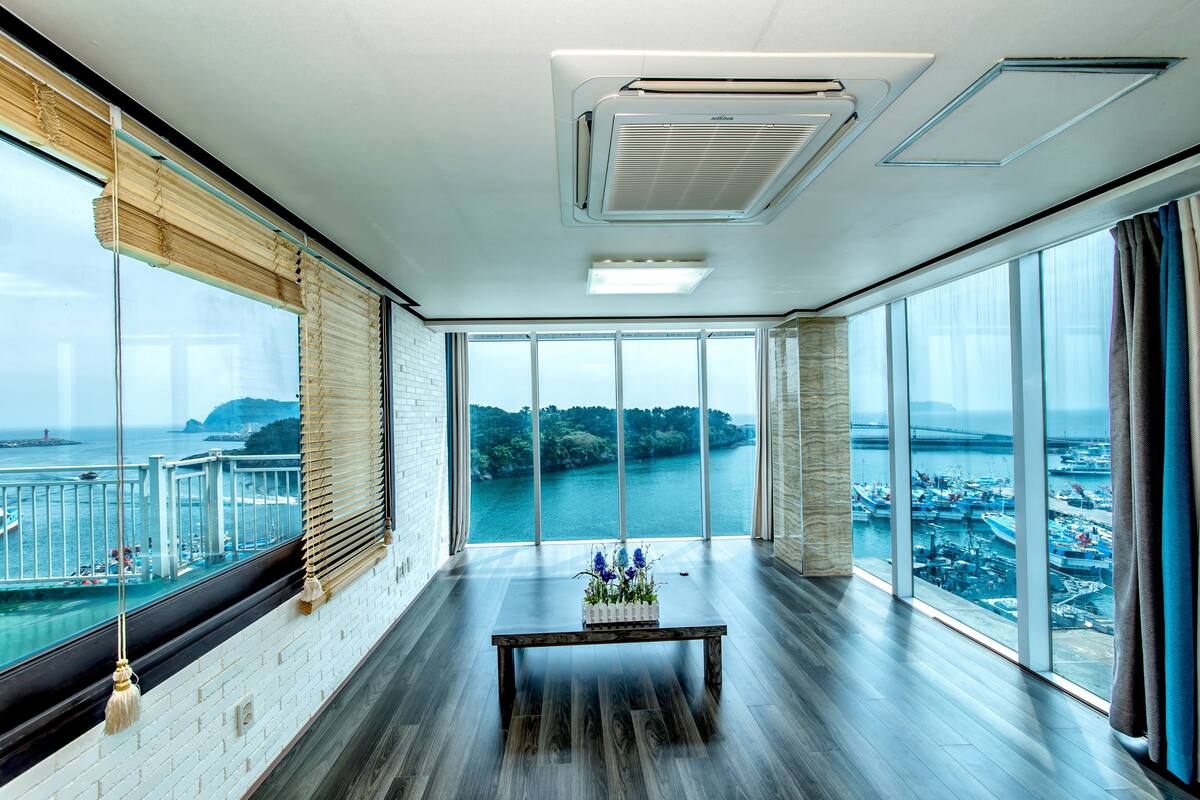 A spacious room with large windows offering a view of a waterfront and a bridge.