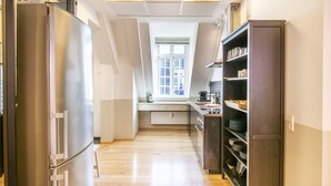 Une cuisine moderne dotée d’un réfrigérateur en acier inoxydable, de meubles en bois et d’une fenêtre laissant entrer la lumière naturelle.