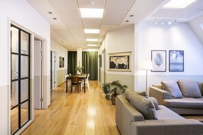 Ein modernes Wohnzimmer mit einer Couch, einem Essbereich mit Tisch und Stühlen sowie Kunstwerken an den Wänden.