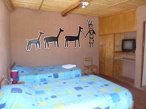 Una habitación con dos camas, un televisor y una pared decorada con dibujos de animales.