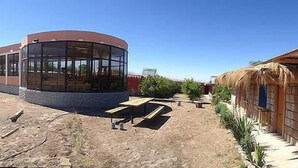 Un edificio con un amplio cerramiento de vidrio y una estructura más pequeña con techo de paja.