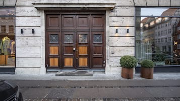 A large wooden double door with glass panels and a small potted plant beside it.