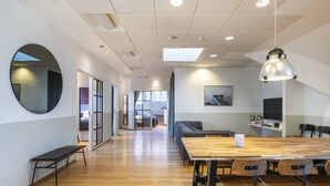 Ett modernt konferensrum med ett långt bord, stolar, en bänk och en hängande lampa.