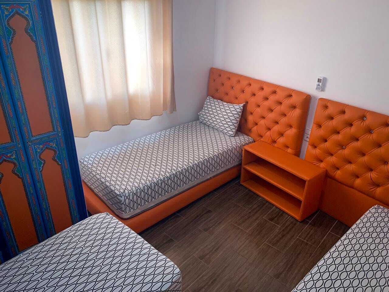 A small room with a single bed, a nightstand, and a chair.