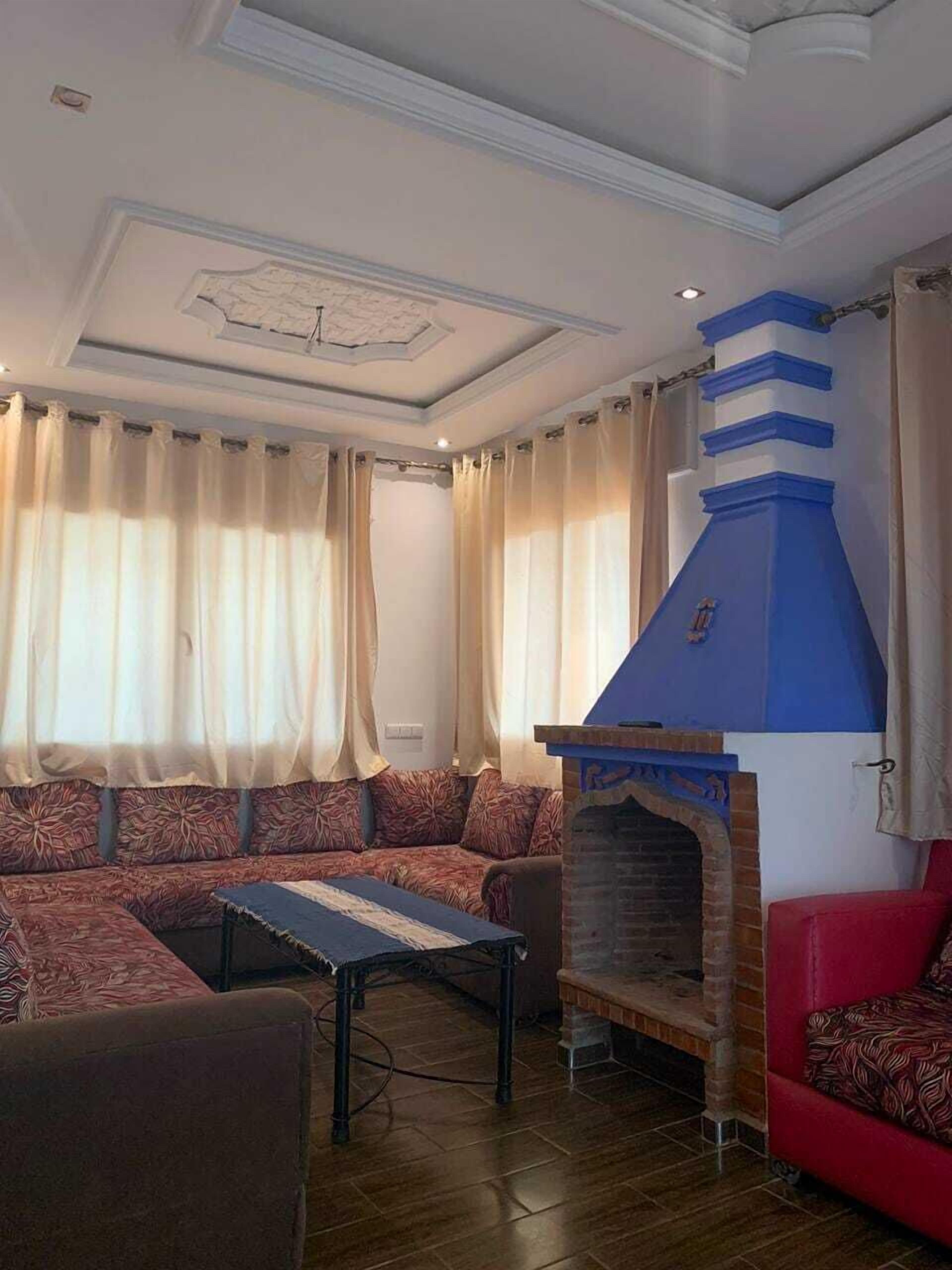 Una sala de estar con chimenea, sofás estampados y un sofá rojo.