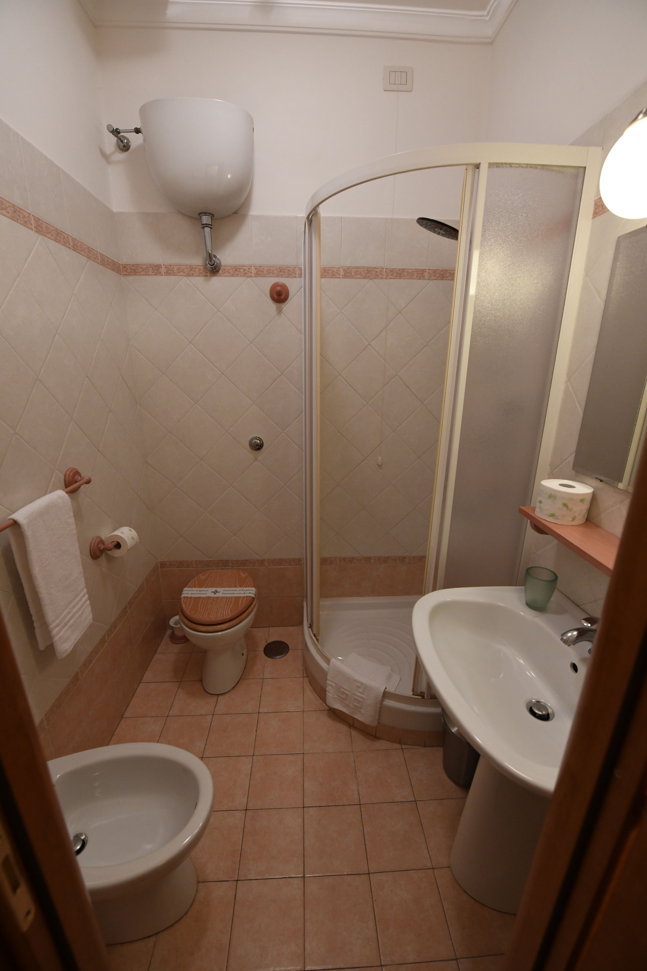A bathroom with a toilet, bidet, sink, and a glass-enclosed shower.