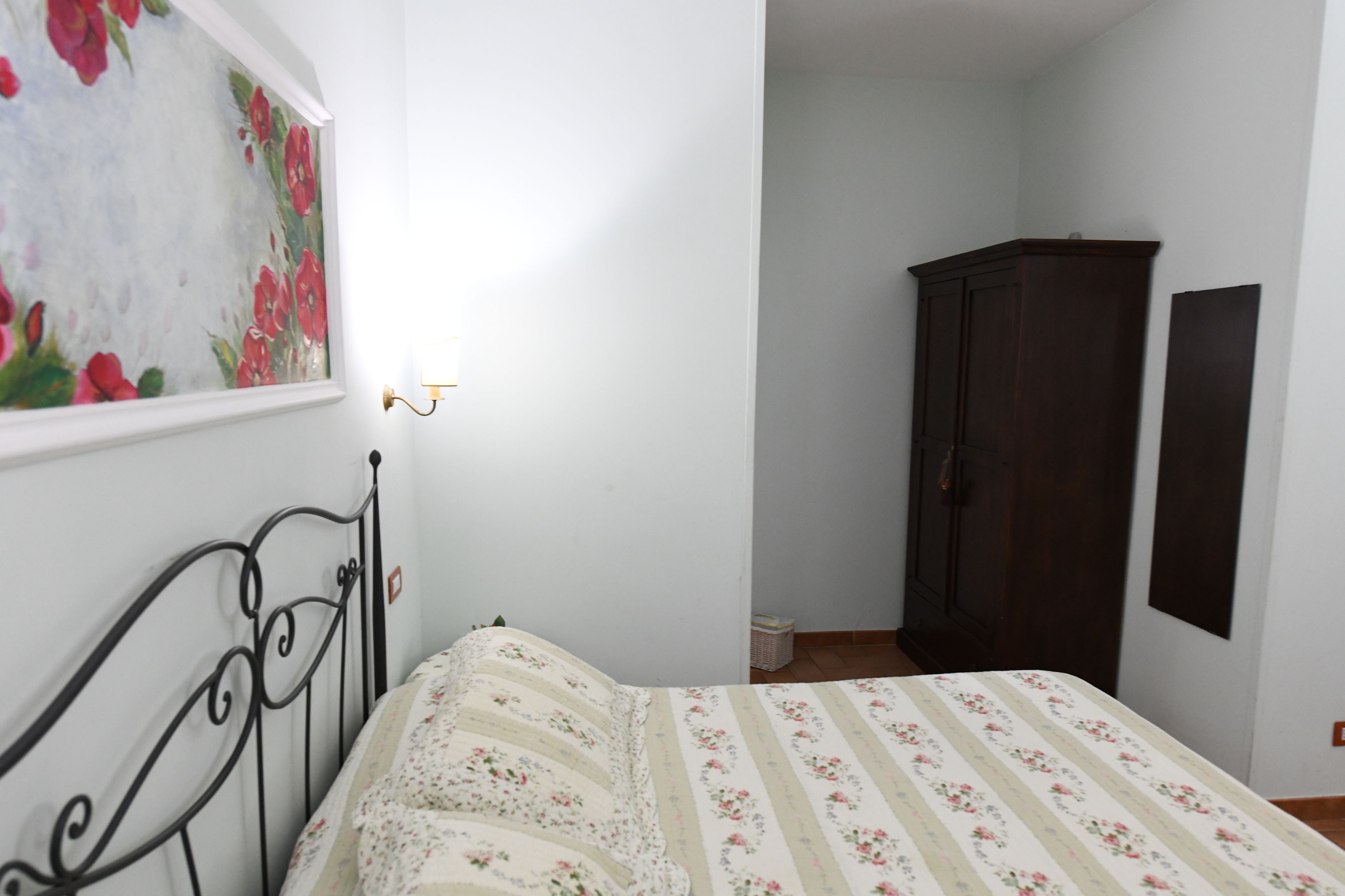 Une chambre à coucher avec un lit, une armoire en bois foncé et un luminaire fixé au mur.