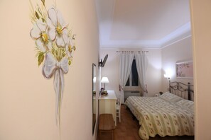 Un dormitorio con cama, escritorio y silla. Hay una ventana con cortinas y una lámpara sobre el escritorio.