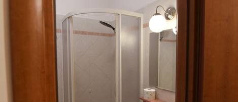 Un baño con ducha envuelta en vidrio, lavamanos y espejo.