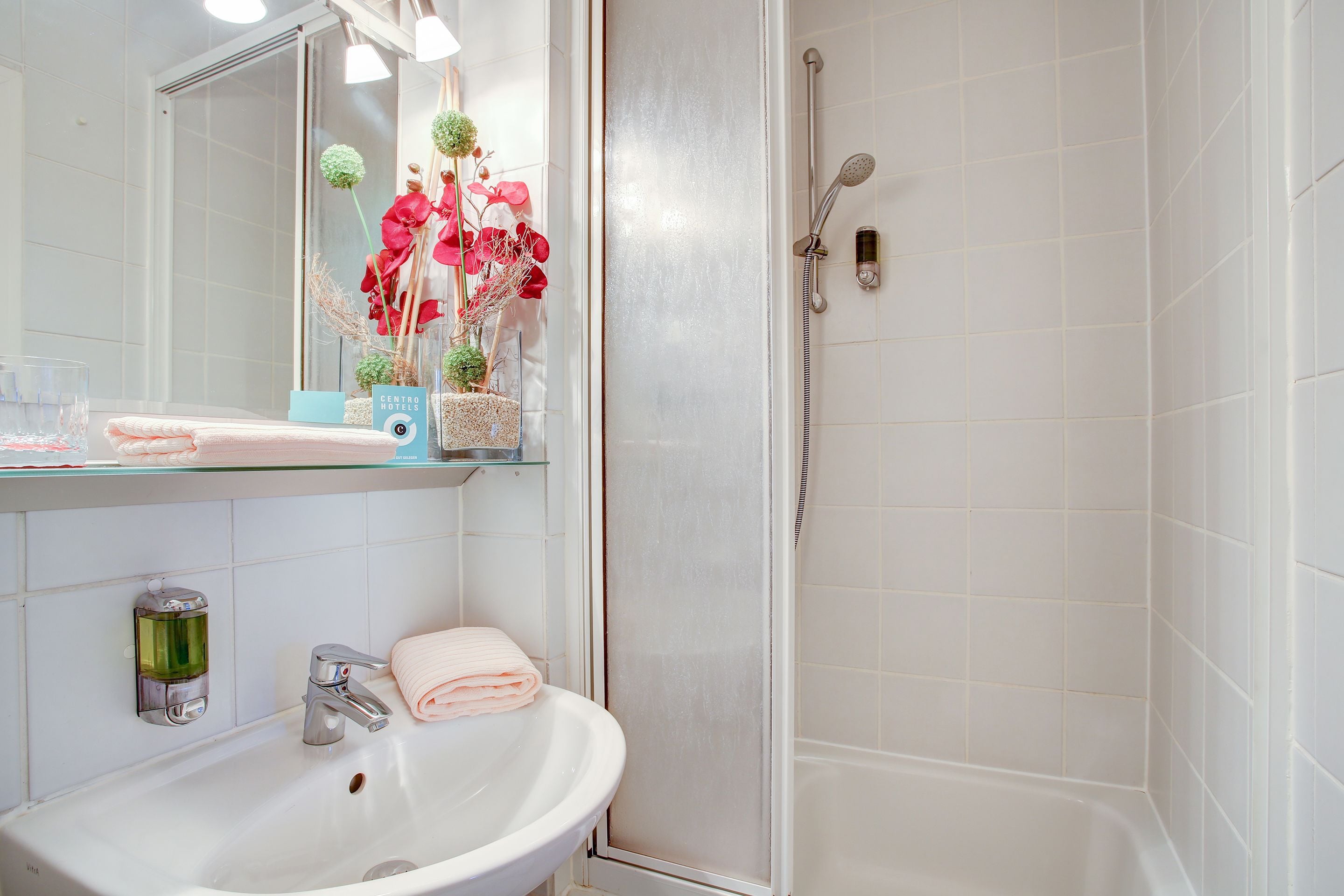 A bathroom with a white sink, mirror, and shower.