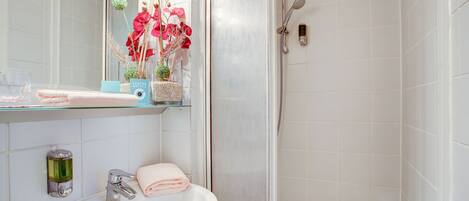 A bathroom with a white sink, mirror, and shower.