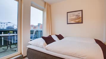 Ein Hotelzimmer mit einem großen Bett, einem Fenster mit Stadtblick und einem Bild an der Wand.