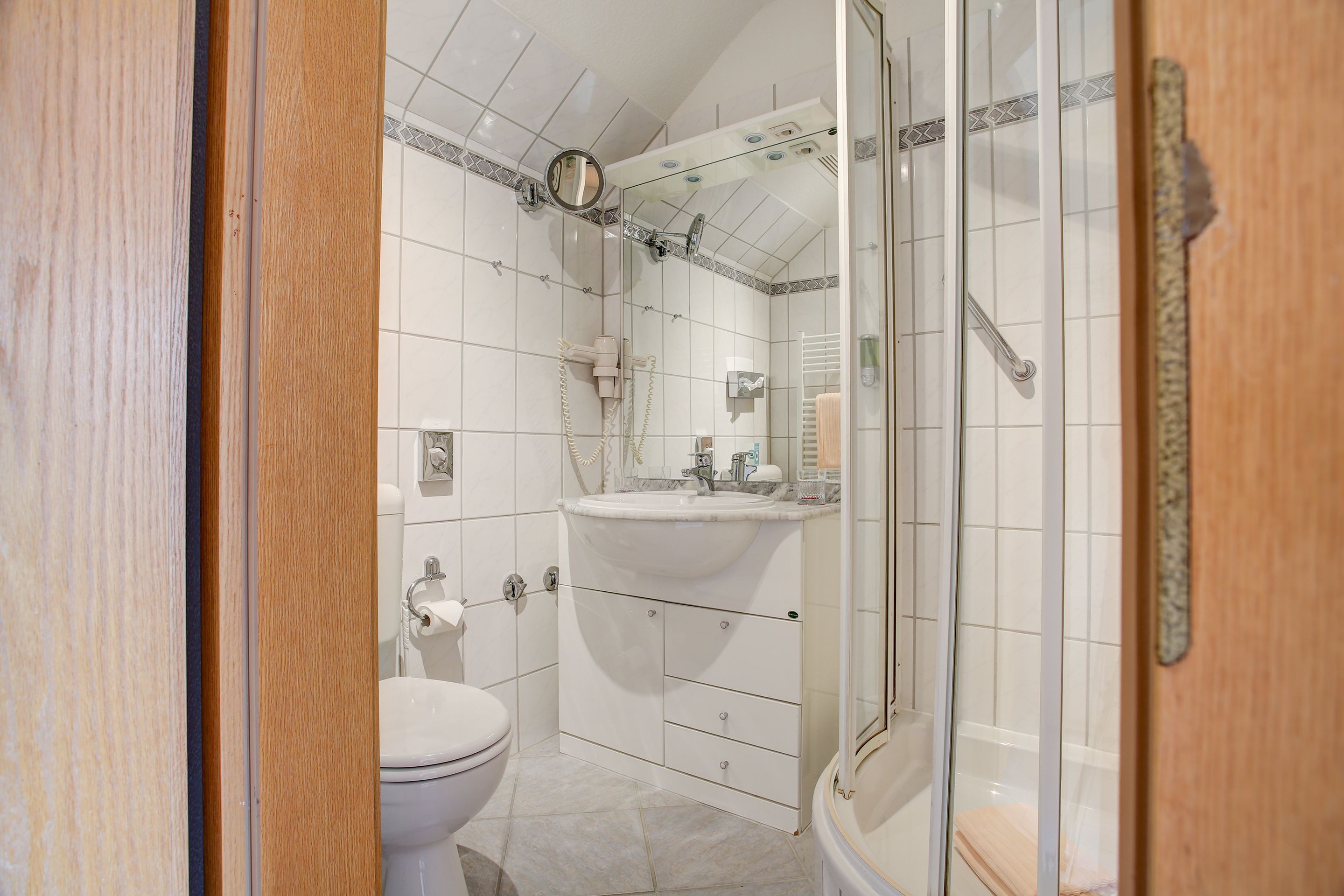 Un baño con inodoro, lavamanos y zona de ducha.