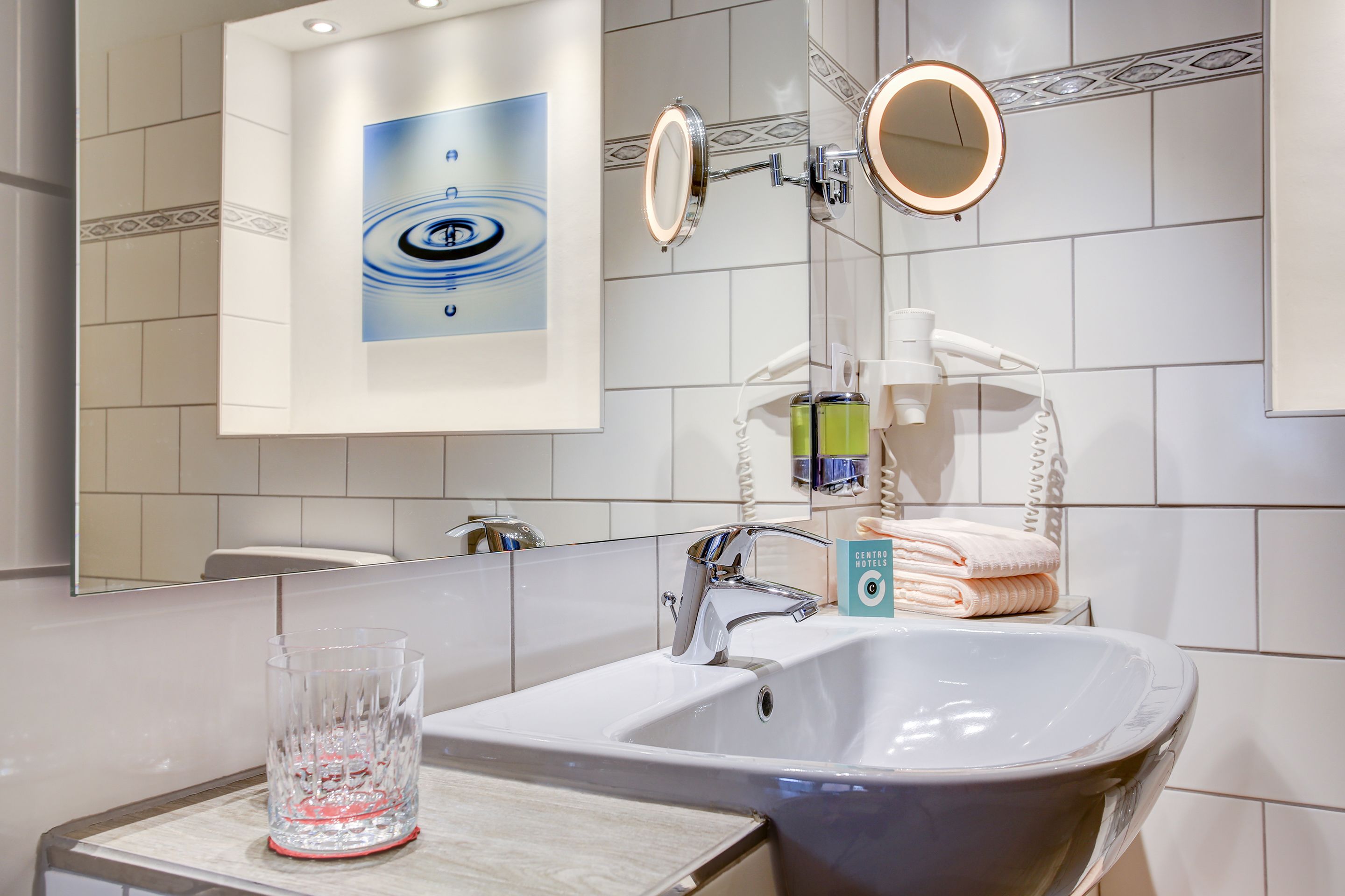 Un baño moderno con un lavamanos grande, dos espejos y un adorno en la pared.