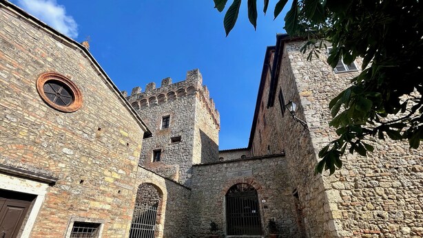 Un bâtiment historique en pierre, doté d’arcades et d’une tour.
