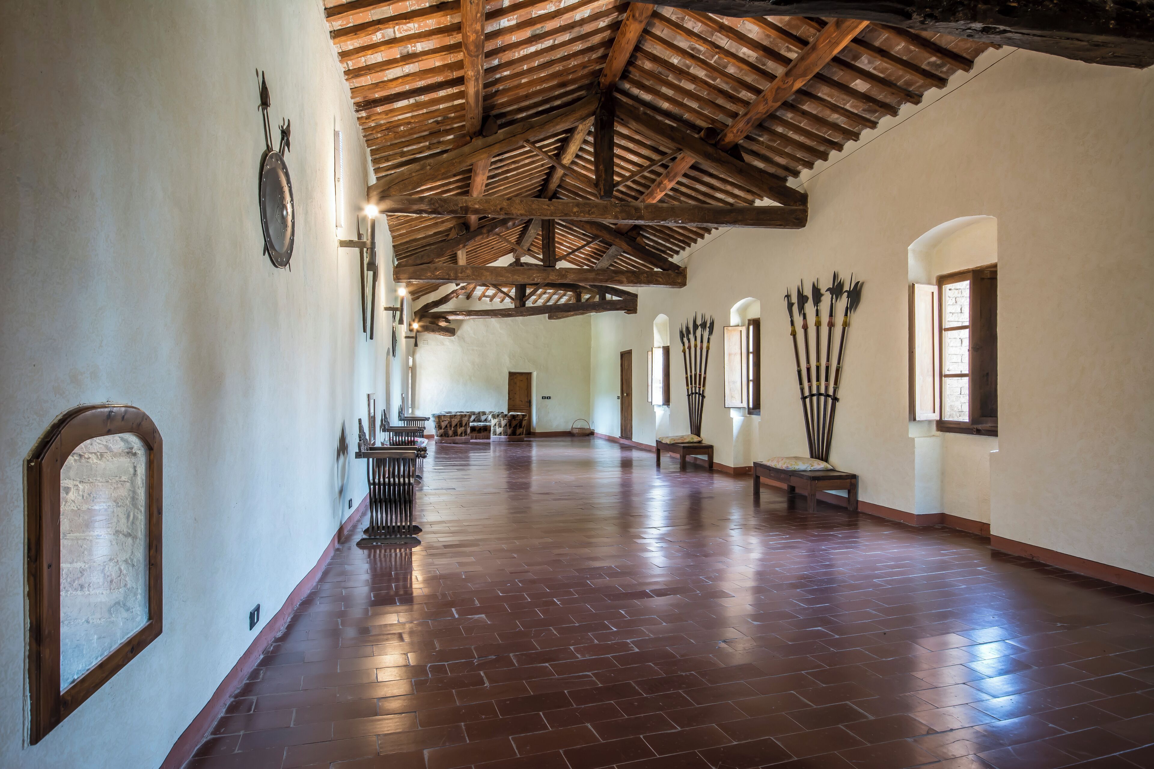 A spacious hallway with a high wooden ceiling and brick flooring.