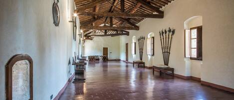 A spacious hallway with a high wooden ceiling and brick flooring.