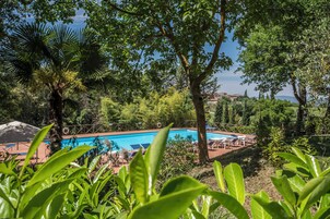 Una piscina rodeada de exuberante vegetación y árboles, con una vista despejada del paisaje circundante.