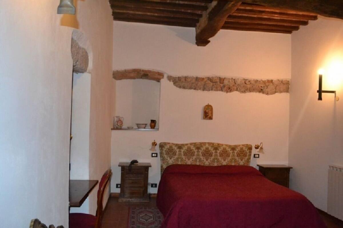 Un dormitorio con cama, cómoda, espejo y repisa de piedra.