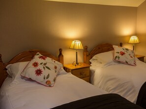 Two beds with wooden headboards, each with a nightstand and a table lamp.