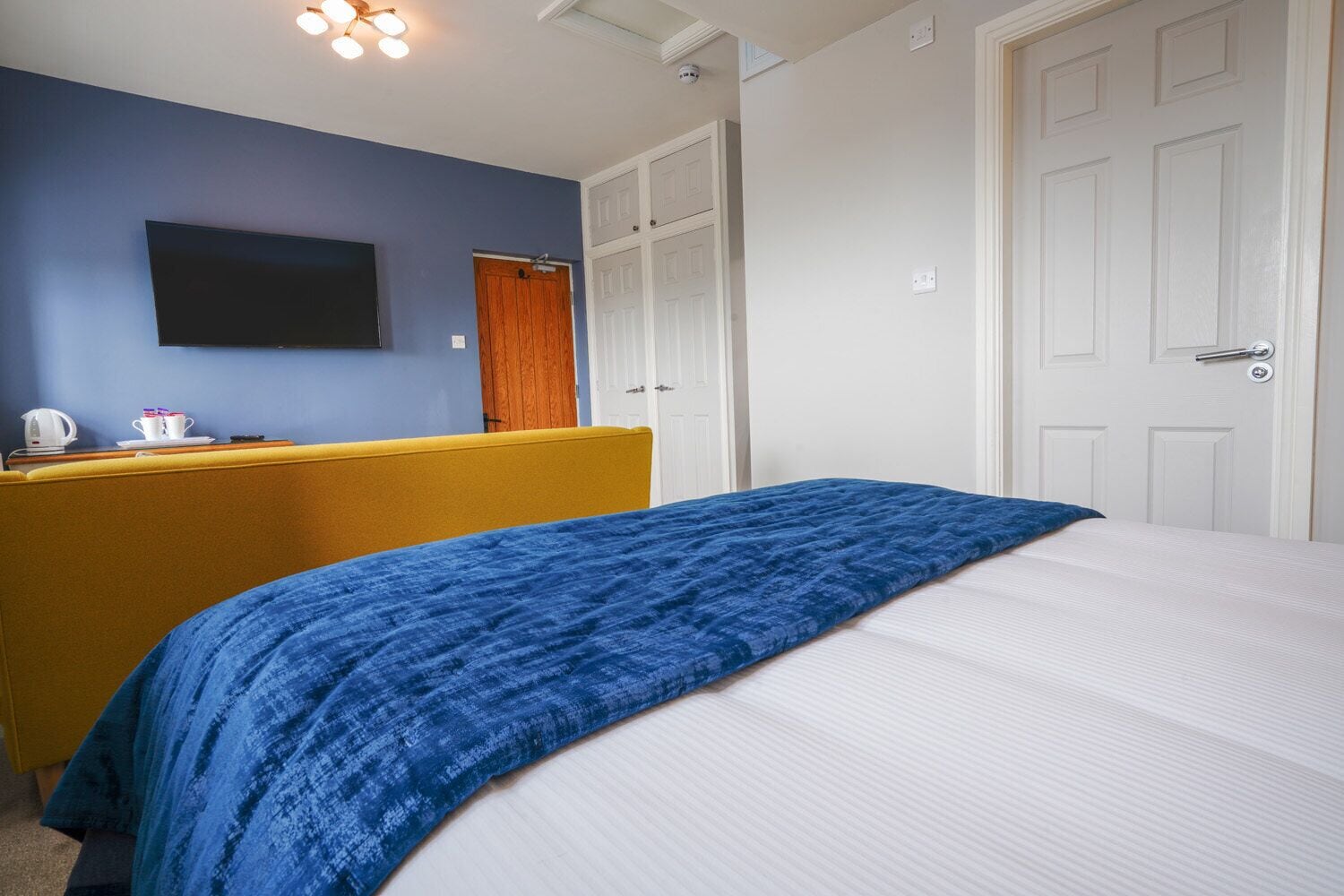 Um quarto com uma cama, uma escrivaninha e um guarda-roupa.