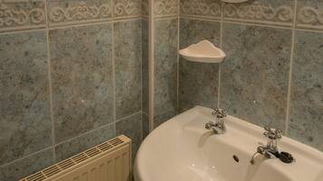 Un baño con un lavamanos blanco, un espejo redondo y azulejos decorativos en la pared.