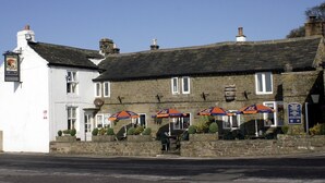 A traditional stone building with a white facade, multiple windows, and outdoor seating with umbrellas. - The Barrel Inn (Hope Valley)