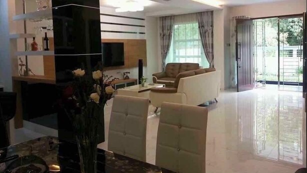 Una sala de estar moderna con sofá, sillas, televisor y zona de comedor.