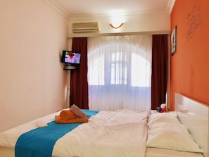 A hotel room with a bed, a TV, an air conditioner, and a window with curtains. - Apartment near Fountain Square (Baku)