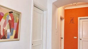 A hallway with white doors, an orange wall, and a framed abstract painting. - Apartment near Fountain Square (Baku)