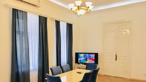 A dining area with a table and chairs, a television, and a door. - Apartment near Fountain Square (Baku)