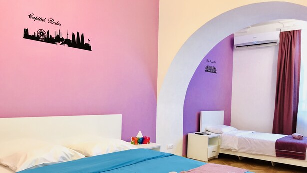 A hotel room with a bed, a nightstand, a desk, and an arched doorway. - Apartment near Fountain Square (Baku)