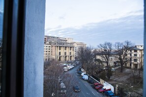 Vista de una calle urbana con edificios, coches aparcados y árboles.