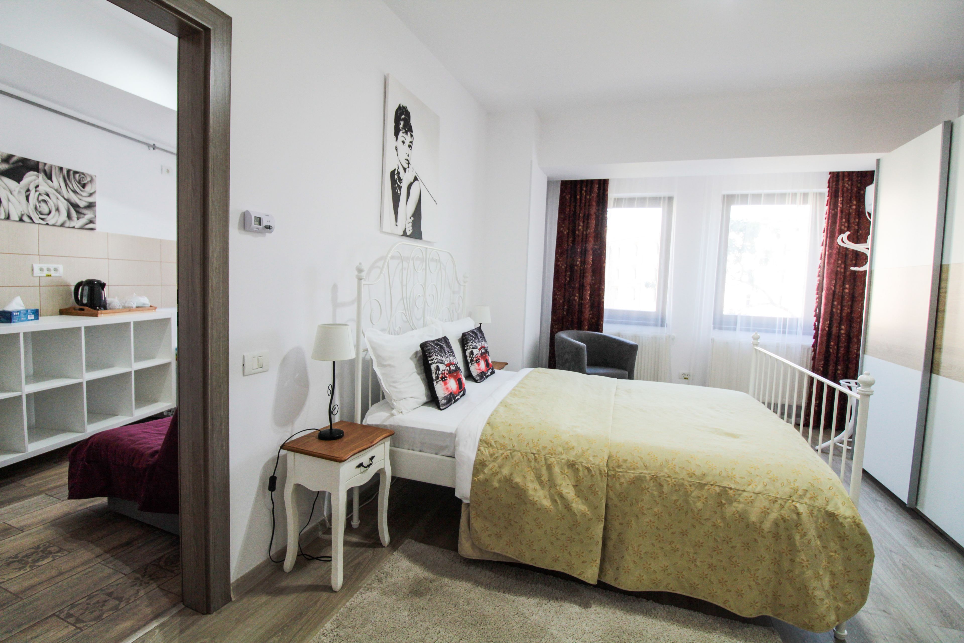 A bedroom with a bed, bedside table, lamp, and a view of the city through the window.