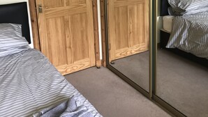 A bedroom with two beds, wooden wardrobes, and a sliding glass door. - 2 Varis Apartments (Forres)