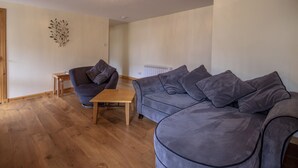 A modern living room with a grey sofa, a wooden coffee table, and a small side table. - 2 Varis Apartments (Forres)