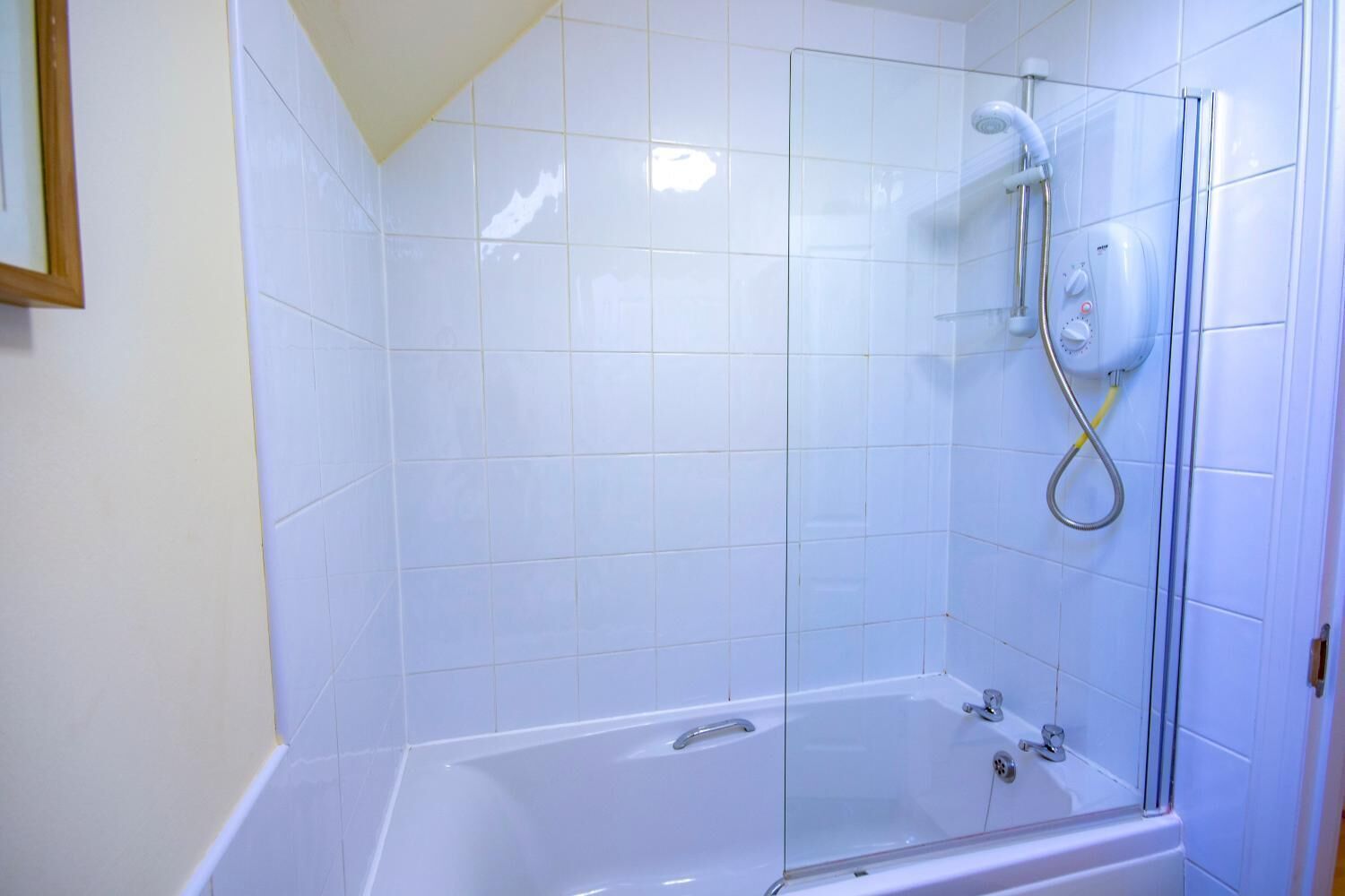 A bathroom with a glass-enclosed shower, a bathtub, and white tiled walls.