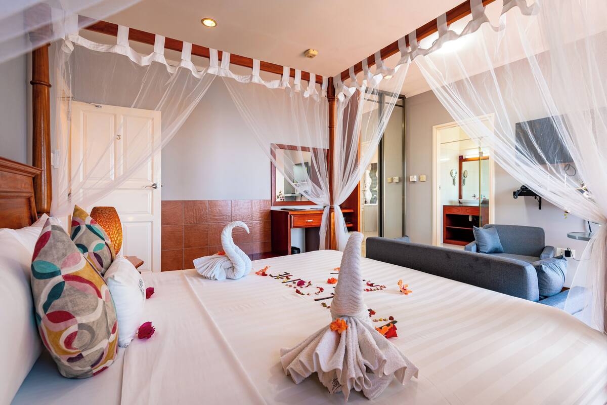 Une chambre d’hôtel avec un lit, un canapé, un bureau et un miroir.