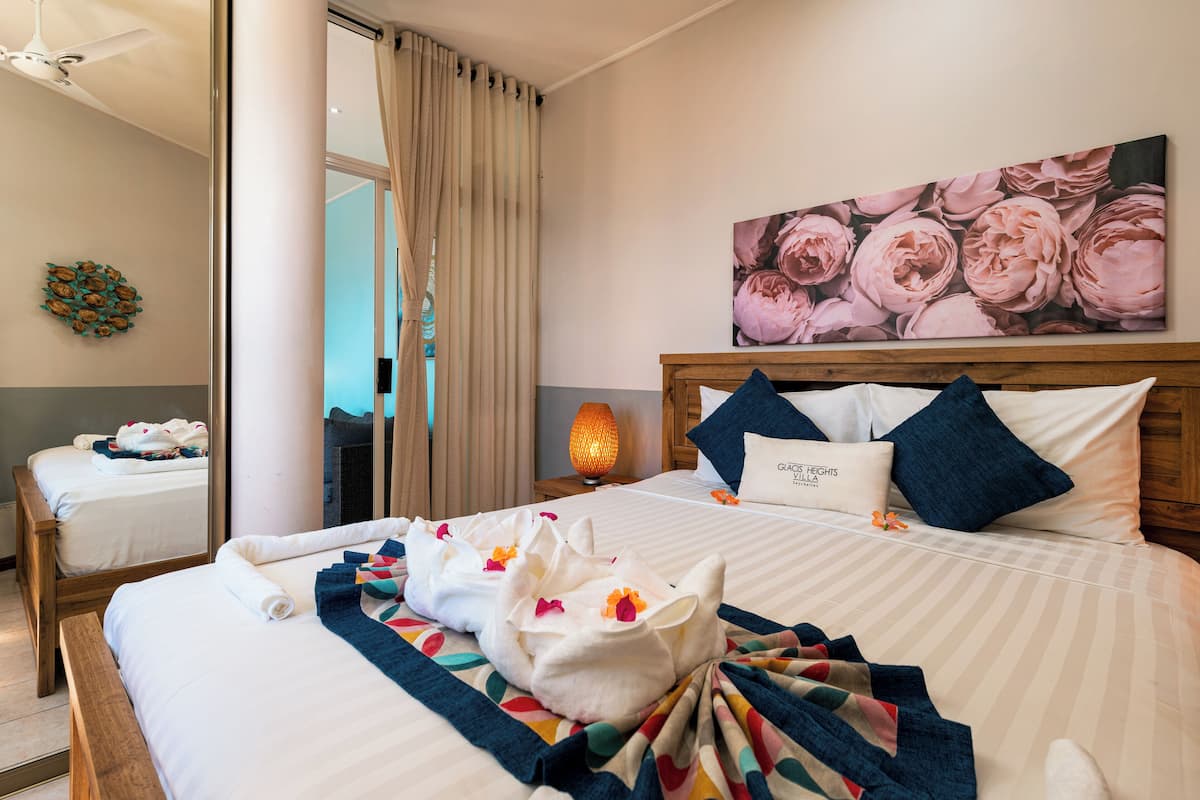 Une chambre d’hôtel avec un grand lit, une table de chevet avec une lampe, un tableau au mur et un miroir.