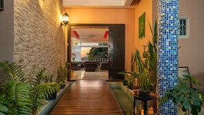 Un sentier en bois mène à un espace aménagé avec des plantes en pot et une lanterne.