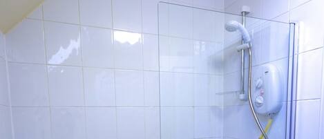 Un baño moderno con bañera de hidromasaje con mampara de vidrio, paredes de azulejos blancos y ducha empotrada.
